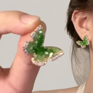 Macro shot of butterfly earrings with green gradient crystals and fine gold setting
