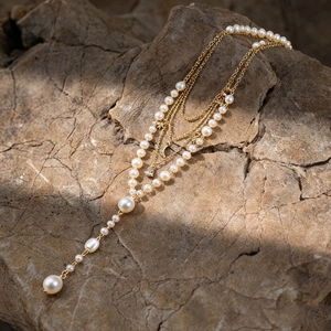 Detailed close-up of layered gold star and moon pendant necklace on a natural stone background