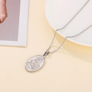 Close-up of silver oval stainless steel necklace with Virgin Mary and Child relief