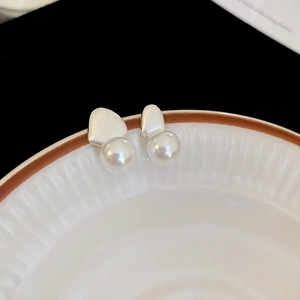 Macro view of minimalist silver irregular geometric earrings with round faux pearls
