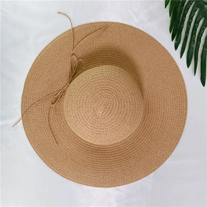 Women's wide brim straw sun hat with delicate bow on elegant white satin and palm leaf