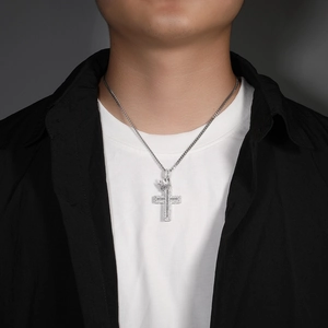 Close-up of silver cross necklace with crown detail and inlaid cubic zirconia stones