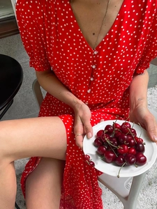 Close-up of V-neckline with pearl buttons and polka dot pattern on red summer dress