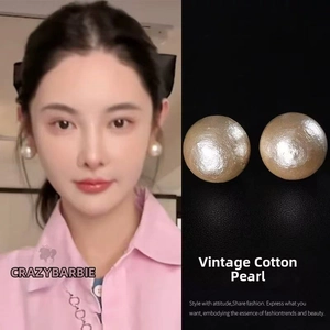 Close-up of retro cotton pearl earrings with a golden base and elegant matte texture