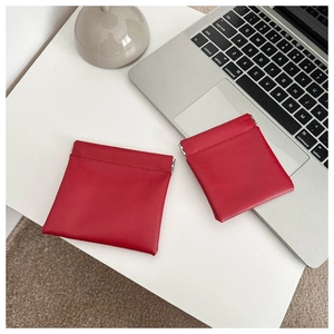 Close-up of red leather mini pouch bags on white desk near a laptop keyboard