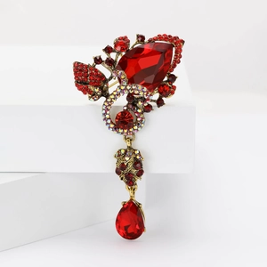 Macro view of vintage gold brooch with red teardrop gemstone and colorful rhinestones
