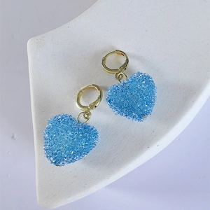 Detail of blue heart earrings with glittering crystals on gold hoop earring bases