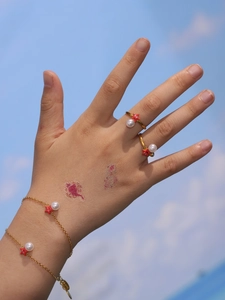 Detalle del sello S925 en pulsera dorada de estrella de mar con perlas usada por modelo
