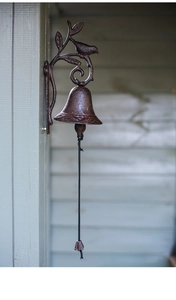 Detailed texture of a rustic cast iron doorbell featuring bird and leaf art on wood