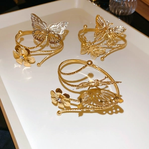 Detailed view of hollow butterfly and floral golden metal bangles with zircon inlay