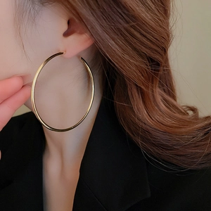 Close-up of oversized gold hoop earring on model with polished metallic finish