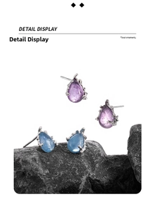 Macro detail of pear-cut purple and blue crystal stud earrings on dark rock