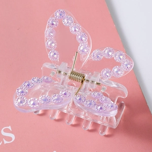 Detailed view of a butterfly hair claw with purple rhinestones on a pink background