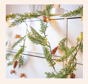 Détail d'une guirlande de pin avec lumières LED chaudes et pommes de pin sur meuble en bois