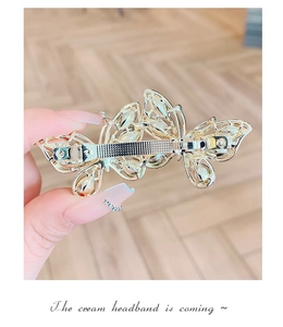 Detail of golden hollow butterfly hair clip with opal stones and spring clamp