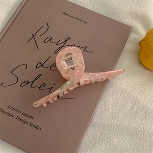 Detailed view of pink marble acetate hair claw clip on art book with a lemon