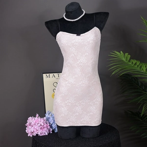 Detalle de textura de encaje floral rosa en un vestido camisero corto ajustado