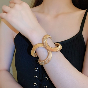 Close-up of golden ribbed metal open cuff bracelet featuring double interlocking bands
