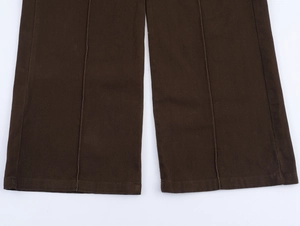 Dettaglio dell'orlo dei pantaloni marrone scuro con trama a saia e cuciture piatte precise