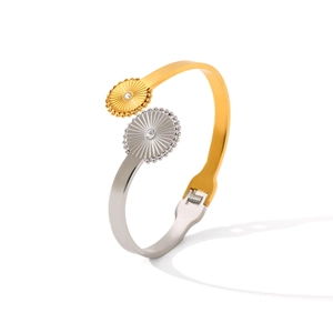 Detail of two-tone stainless steel open bangle with sunburst discs and zircons
