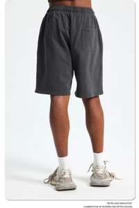 Detail of grey washed cotton shorts featuring elastic waist and back pocket on white background