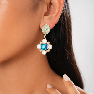 Macro view of vintage-style oval drop earrings with deep blue stone and floral details