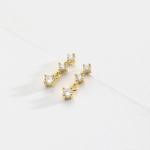 Elegant gold drop earrings with three graduated cubic zirconia stones on white background