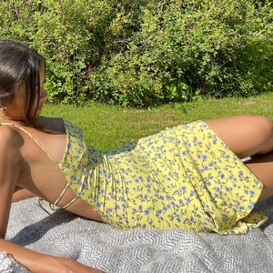 Detail of floral backless dress with side slit on grass in natural outdoor light