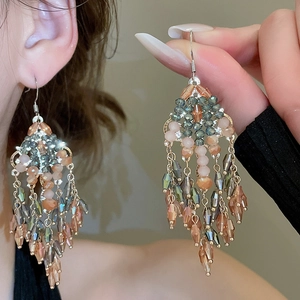Détail de boucles d'oreilles bohèmes vintage à pompons en perles or et bleu foncé