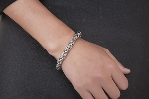 Macro shot of silver Byzantine chain bracelet in stainless steel on a male wrist