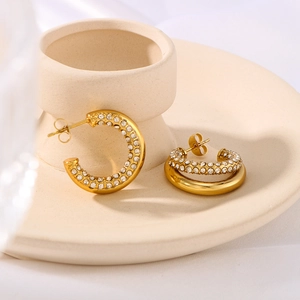 18K gold plated C-shaped stud earrings with micro-inlaid cubic zirconia on a ceramic tray