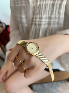 Detailed shot of golden octagonal watch with chain ring and diamond dial markers