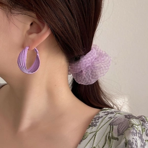 Elegant multi-layered matte purple C-shaped earrings worn by a model in a close-up view