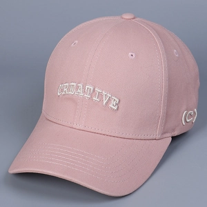 Detail of pink cotton baseball cap featuring 3D white CREATIVE embroidery and curved brim