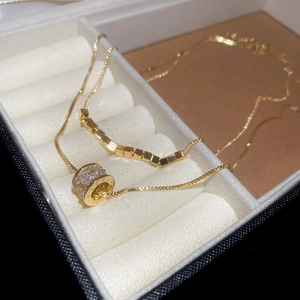 Detailed macro view of 18k gold plated double layer necklace with cubic zirconia cylinder