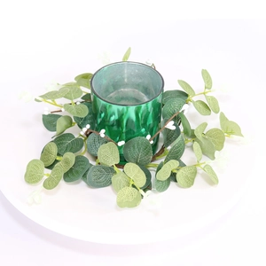 Close-up of green cracked glass candle holder with eucalyptus and berry wreath