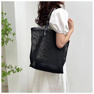 Detail view of black mesh beach tote bag with breathable texture and leather shoulder strap