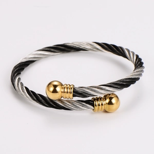 Detail of twisted cable cuff bracelet in black and silver steel with gold ball ends