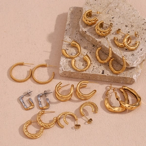 Collection de boucles d'oreilles dorées et argentées sur un socle en pierre naturelle