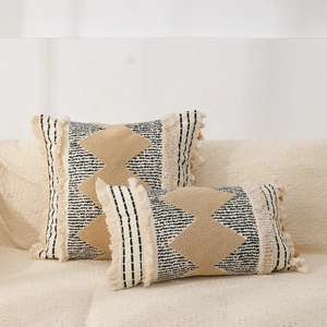 Close-up of Bohemian tufted pillow covers with black stripes and beige tassels on sofa