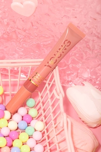 Close-up of pink liquid lip gloss tube in a miniature basket with decorative beads