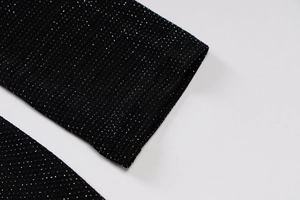 Gros plan du tissu en maille noire avec fils argentés scintillants et détails de manche