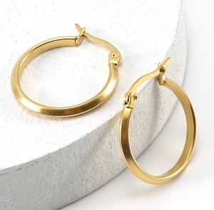 Close-up of classic 18K gold-plated stainless steel hoop earrings on stone display