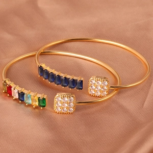 Detail van verstelbare gouden armbanden met gekleurde edelstenen en zirkonia op zijde
