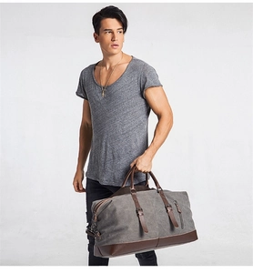 Close-up of grey canvas travel bag with brown leather trim and metal buckles detail