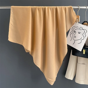 Detail of a khaki linen scarf hanging on a metal hanger with a soft textured finish
