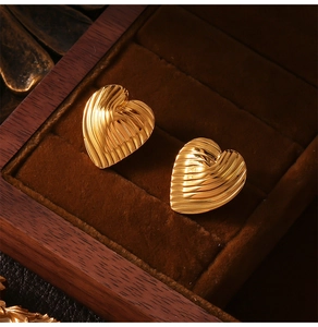 Detailansicht goldener Herzohrringe mit Linientextur in einer antiken Schmuckschatulle