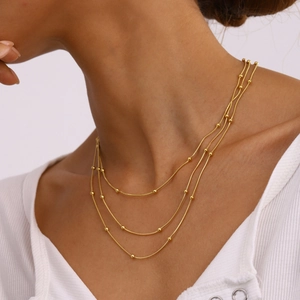 Detailed view of layered gold bead snake chains on neck showing elegant metal texture