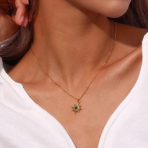 Macro detail of gold-plated starburst necklace with green zircon gemstone on model