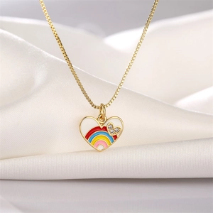 Detalle de collar de corazón dorado con esmalte arcoíris y gemas sobre seda